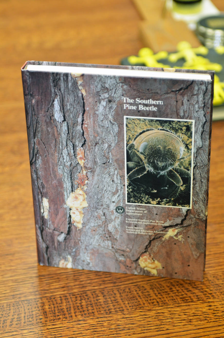 While at Texas A&M, Tom Payne serves as the research coordinator of the Southern Pine Beetle Program, sponsored by the USDA. Pictured is a book that resulted from the project's research. On the cover is a photo of a beetle that Tom took. Photo by Stephen Schmidt.