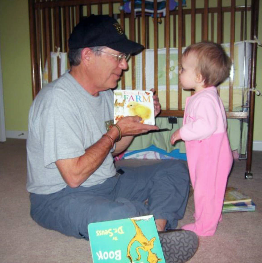 CAFNR Dean Tom Payne shows his toddler granddaugther, Caroline, who is now 11, a book about farm animals. Photo courtesy of Jacob Payne.