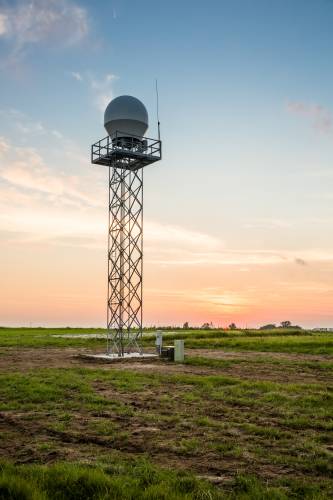Weather radar tower at sunset. The sky is a faded blue and pink.